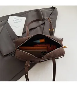 Detail of the spacious interior of a dark brown suede shoulder bag holding daily essentials