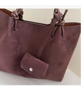 Detail of burgundy suede tote with knotted handle and matching mini coin purse attachment