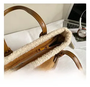 Detailed shot of brown faux suede tote bag with white faux fur trim and gold metal hardware