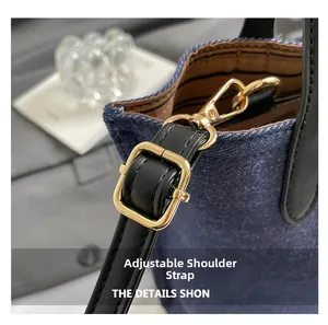 Detail of adjustable black leather strap with gold metal buckle on blue denim bucket bag