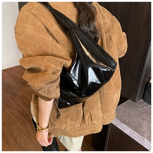 Detail of a large black patent leather Hobo bag with high-gloss finish and wide shoulder strap