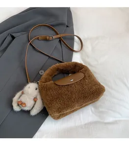 Detailed close-up of brown plush crossbody bag with leather flap and rabbit pendant