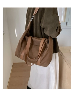 Detail of canvas tote with brown leather strap and silver metal chain link decoration