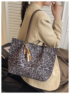 Dettaglio borsa leopardata con ciondolo in perle di legno e spalline in pelle marrone