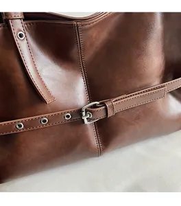 Detail of dark brown leather texture and silver buckle on a minimalist tote bag