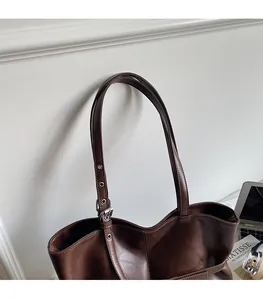 Detail of dark brown leather tote with silver metal eyelets and adjustable double straps