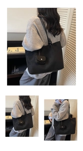 Detail of a large black matte tote bag featuring a matching mini coin purse and knotted strap