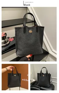 Détails d'un sac cabas en toile noire avec poignées en cuir et fermoir doré rotatif