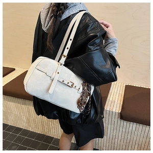 Close-up of white shoulder bag with pebble grain leather texture and metallic buckle strap