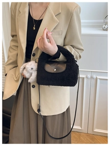 Detail of black plush mini handbag with leather flap and cute rabbit charm on side