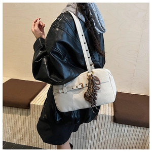 Detail of cream shoulder bag with metallic eyelets on strap and brown letter charm