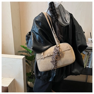 Detailed view of vintage beige shoulder Boston bag with stylish charm accessory and buckle strap.