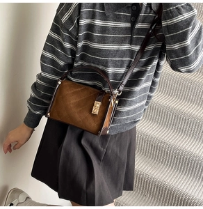 Detail showing the brown suede crossbody bag with quilted diamond pattern and gold buckle
