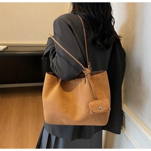 Detail of a brown suede tote bag featuring a slim shoulder strap and mini hanging pouch