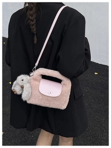 Outdoor shot of pink plush handbag with leather flap and cute rabbit charm detail