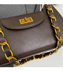 Détail du sac à chaîne en cuir marron foncé avec fermoir doré et texture fine