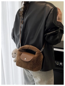 Detail view of brown faux fur crossbody bag with leather flap and plush doll charm