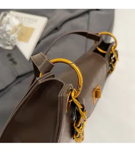 Détail du sac en cuir marron foncé avec boucle circulaire dorée vintage et chaîne épaisse