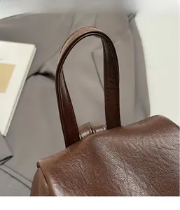 Dettaglio ravvicinato del manico in pelle marrone con trama litchi e patta della borsa