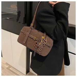 Close-up of retro brown suede underarm bag with metal buckle and matte leather texture