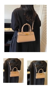 Détail d'un sac à bandoulière rose avec fermoir doré sur une tenue de blazer noir
