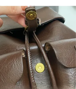 Dettaglio borsa in pelle marrone con chiusura magnetica dorata e texture martellata