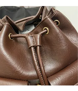 Dettaglio borsa a secchiello marrone scuro con coulisse in pelle e occhielli dorati
