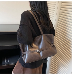 Detail of dark brown tote bag with retro belt buckle decoration and vintage leather texture