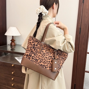 Detail of leopard print tote bag with brown leather straps and matching mini pouch