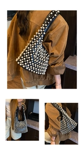 Detail einer schicken Tasche mit großen weißen Perlen auf schwarzem Leder und breitem Gurt