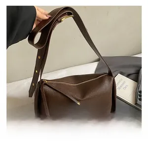 Vue détaillée du sac cylindrique en cuir marron foncé avec large bandoulière réglable