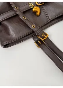 Dettaglio borsa tote vintage marrone con fibbie dorate e ciondolo a forma di cuore