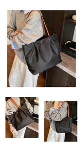 Detail of black nylon tote bag featuring gold snap button and brown leather shoulder straps
