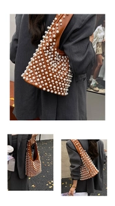 Detailansicht einer braunen Ledertasche mit eleganten weißen Perlenverzierungen