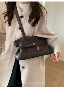 Detail der dunkelbraunen Retro-Tote-Bag mit goldener Schnalle und kommaförmigem Anhänger