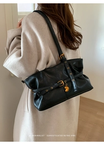 Dettaglio laterale di una borsa tote retrò in pelle nera con finiture dorate e cuore