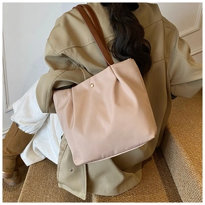 Detail of light pink pleated tote bag with golden buckle and brown leather strap