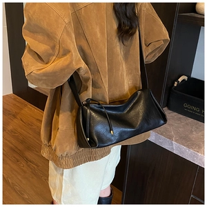 Gros plan du sac baguette en cuir souple noir montrant la texture et les détails du zip