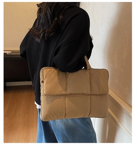 Close-up of quilted puffy shoulder bag in khaki showing soft texture and padded handle