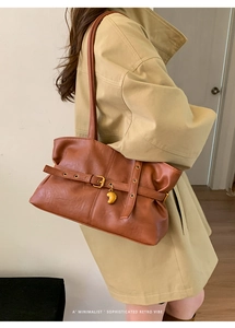 Dettaglio borsa tote retrò marrone con cintura decorativa e ciondolo in metallo dorato