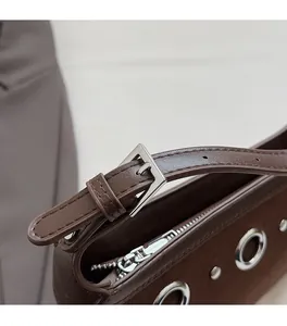 Detail of dark brown suede handbag featuring silver metal hardware and leather strap