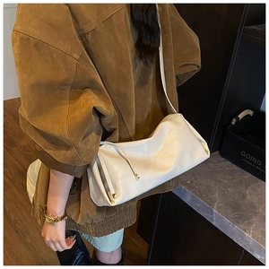 Détail du sac baguette blanc avec cordon de serrage latéral et ferrures dorées
