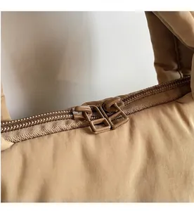 Macro detail of smooth dual zippers and quilted fabric texture on the beige puffer tote bag