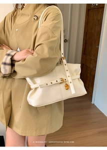 Dettaglio borsa a spalla bianco sporco con ciondolo dorato e trama vintage retrò