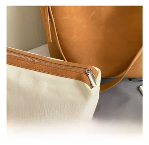 Detailansicht des silbernen Metallreißverschlusses und der braunen Lederpaspel an der Tasche