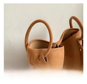 Detailaufnahme der karamellfarbenen Wildledertasche mit verstärkten zylindrischen Griffen