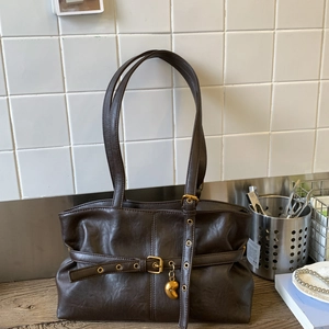 Dettaglio della borsa a spalla in similpelle marrone con trama vintage e fibbia dorata