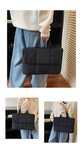 Macro detail of black quilted puffer tote bag showing soft square texture and top handle