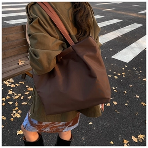 Detail of large brown tote bag with leather straps styled in an autumn street scene