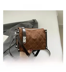 Close-up of brown suede crossbody bag with diamond quilting and silver stud accents